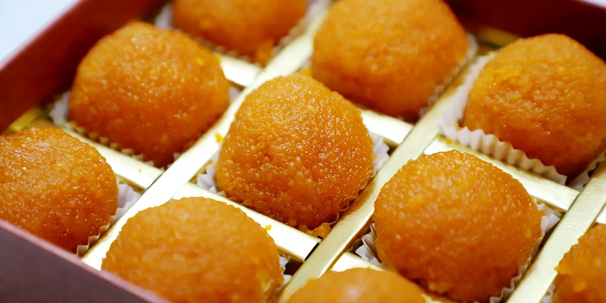 Golden-yellow-coloured textured Laddus are neatly arranged inside a decorative box