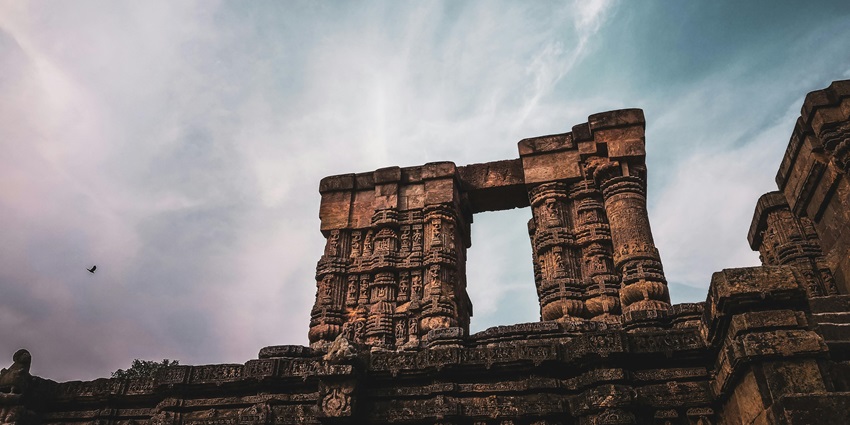 An architectural detail of an old Hindu temple with ornate carvings and a towering spire.