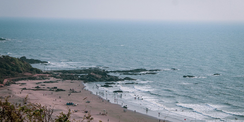 An aerial view of sprawling blue waters of Vagator Beach hitting the golden sands.