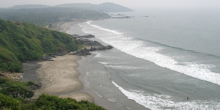 A picture of a beach taken from a distance with an Island visible in the background