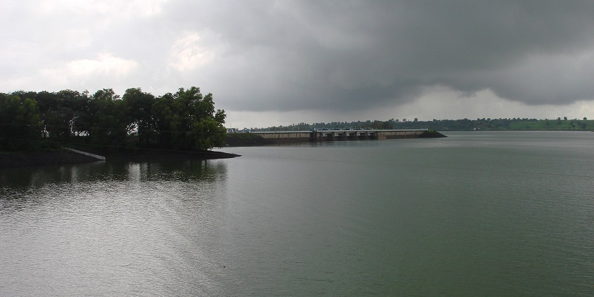 Scenic view of Vaitarna River with calm waters, surrounded by lush greenery and hills under a clear sky