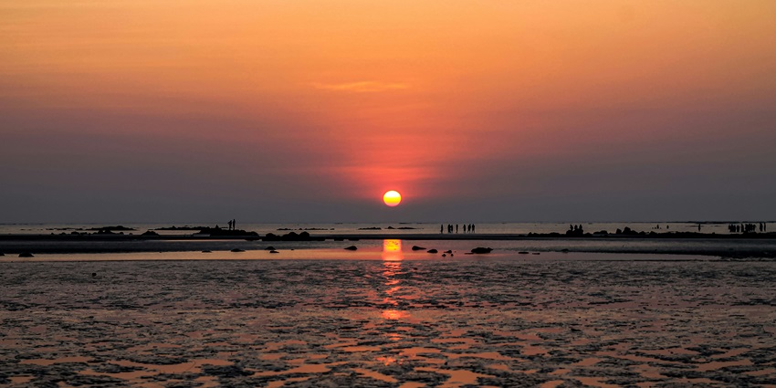 A scenic vista of the Varsoli Beach with shades of red and orange spread all over the sky.