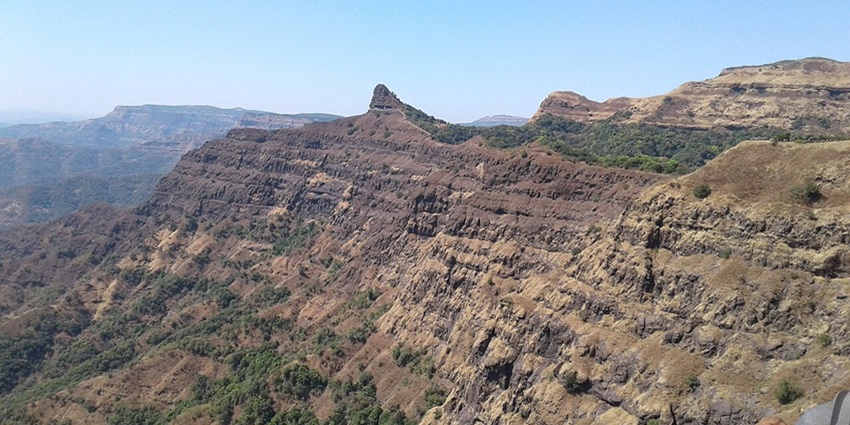 An image of the ancient Vasota Fort surrounded by dense forest in Satara.