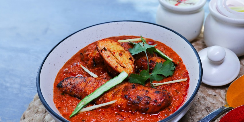 Masala Chaap in red gravy garnished with sliced chilli and coriander served in a bowl