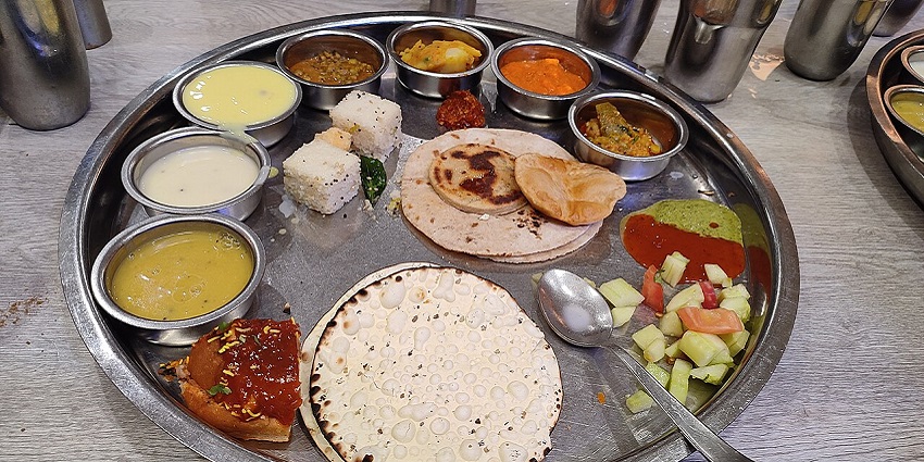 A Vegetarian thali, consisting of curries, rice, roti, papad, dhokla, pickle, and salad.