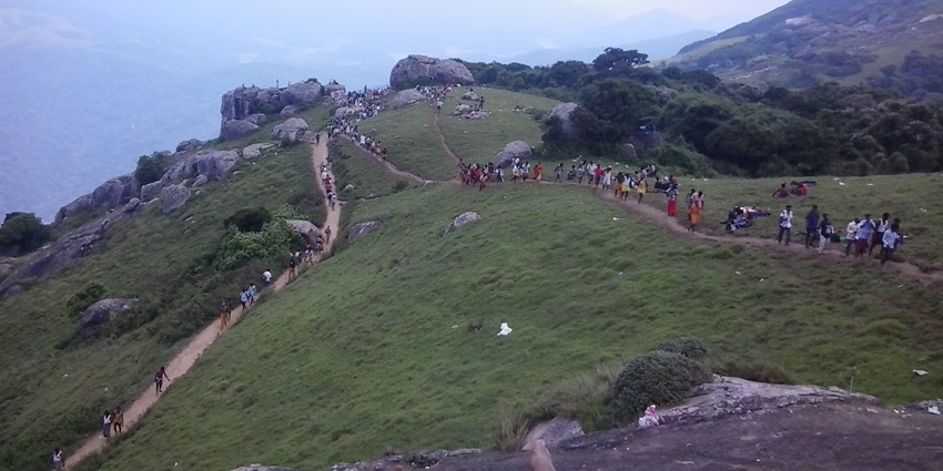 A picture of a long queue of devotees climbing a hill to visit a hilltop temple to offer prayers