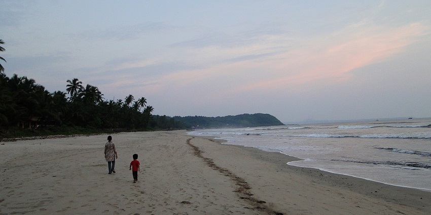 A tranquil view of Velneshwar Beach during the monsoon, surrounded by lush greenery.