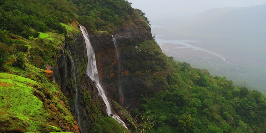 Vihigaon Waterfall cascading down, surrounded by dense greenery