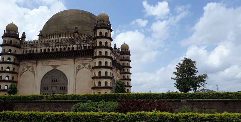 A picturesque garden view with Gol Gumbaz, one of the best things to do in Vijayapura.