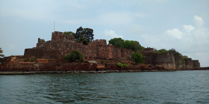 A landscape view of the Vijaydurg Fort, surrounded by the Arabian Sea on three sides