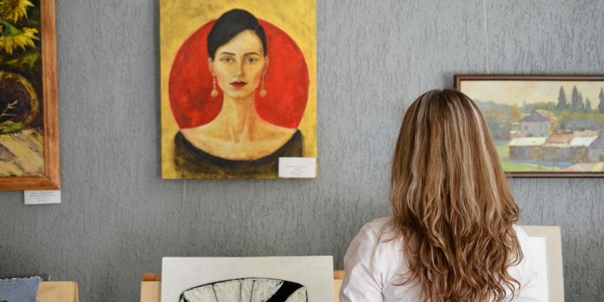 Image of a woman Looking At Paintings Displayed On The Wall