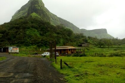 View of Visapur Fort on a hilltop surrounded by greenery under a cloudy sky in Maharashtra.