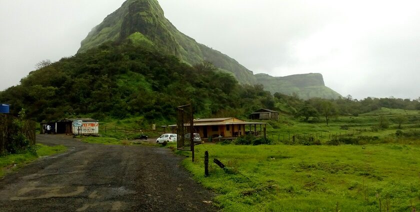 View of Visapur Fort on a hilltop surrounded by greenery under a cloudy sky in Maharashtra.