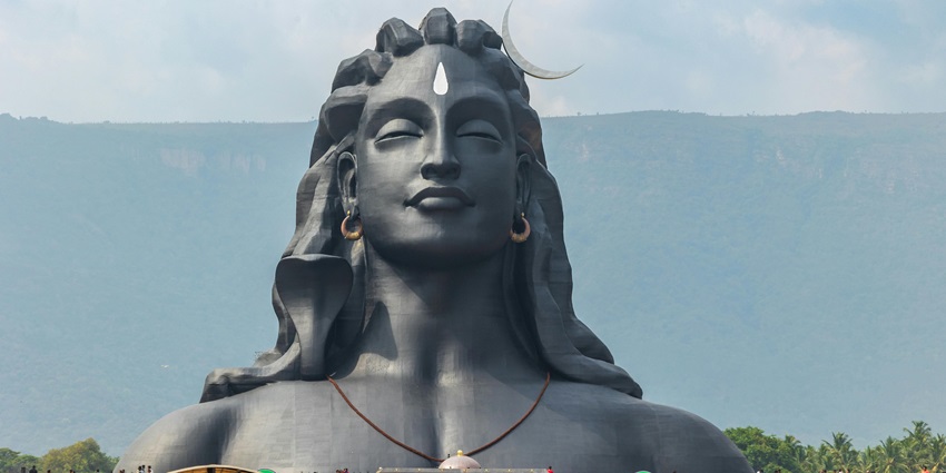 An image of the Adiyogi Shiva statue, set against a backdrop of hills and greenery