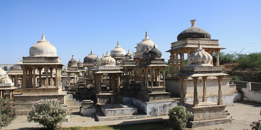 Stone cenotaphs at Ahar Museum in Udaipur, featuring intricate domes and pillars with garden.