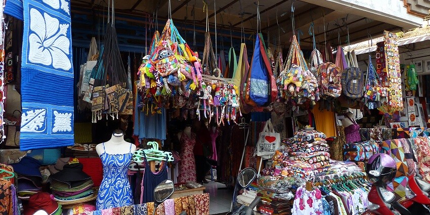 A shop in Bali market selling colourful slings bags of various sizes, garments, and shawls