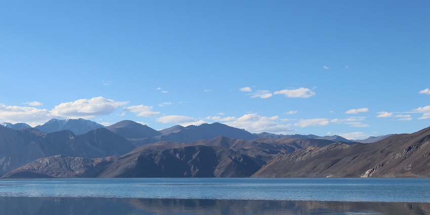 A picture of a beautiful lake with a reflection of the mountains behind it falling on the surface.