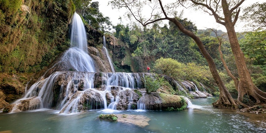 A glimpse of Pawa Waterfalls cascading down amidst vibrant green surroundings.