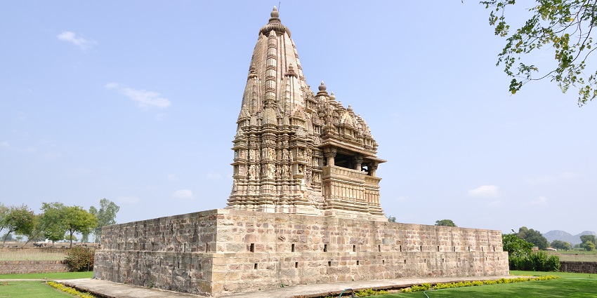A glimpse of a towering temple surrounded by lush green vegetation in Madhya Pradesh.