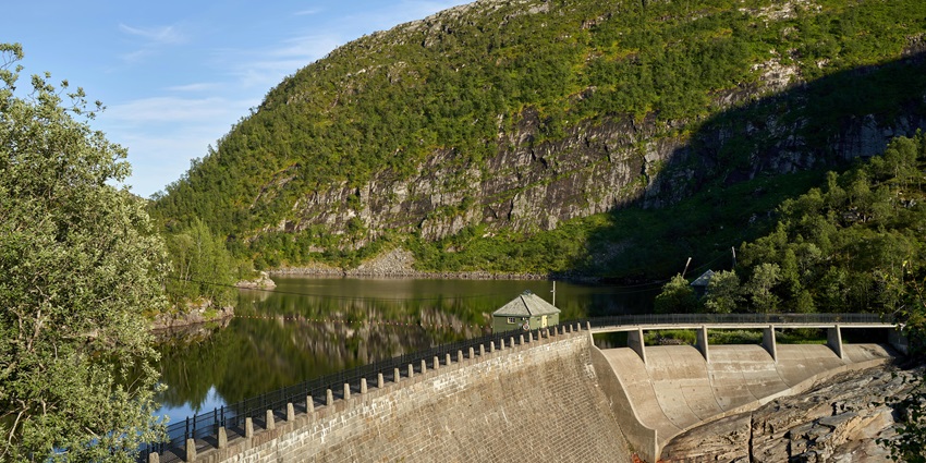 A scenic view of Bhira Dam, with tranquil waters, majestic hills, and lush greenery.