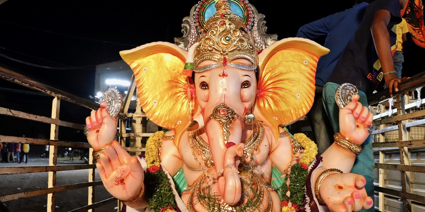 An image showcasing the vibrant Lord Ganesh idol that is adorned with flowers and ornaments