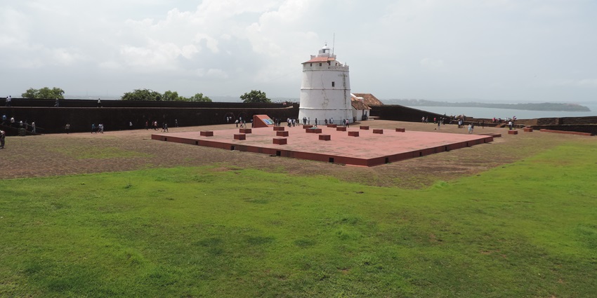 A picture of a lighthouse in Varca Goa with lush greenery and a beach in sight