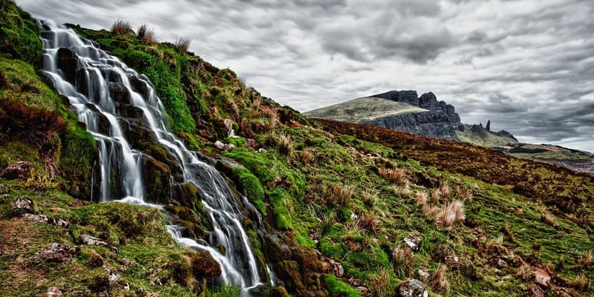 Captivating view of waterfalls surrounded by dense forest and rocky cliffs.
