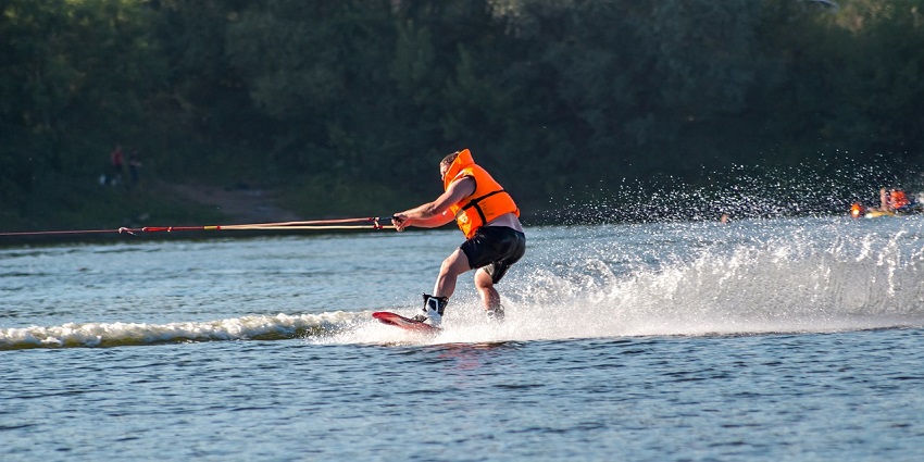A picture of a wakeboarder performing tricks while being towed by a speedboat.