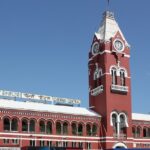 Chennai train station with people waiting on the platform and trains on the tracks.