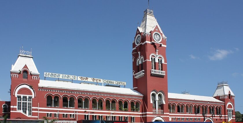 Chennai train station with people waiting on the platform and trains on the tracks.