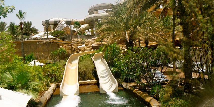 A water park with thrilling water slides surrounded by palm trees, one of the top places to visit in Kuta.