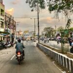 A wide road lined with trees in Amaravathi, India, showcasing greenery and a clear sky