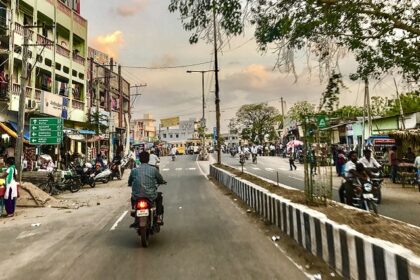 A wide road lined with trees in Amaravathi, India, showcasing greenery and a clear sky