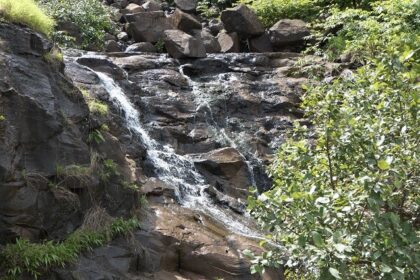 A scenic view along Tamhini Ghat featuring lush green mountains and winding roads.