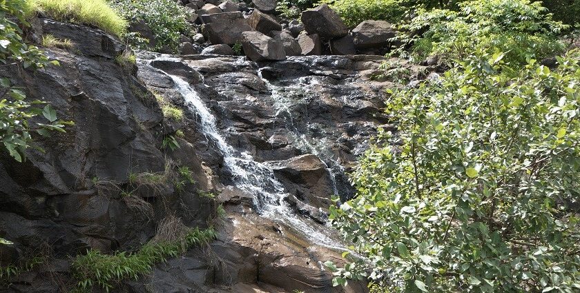 A scenic view along Tamhini Ghat featuring lush green mountains and winding roads.