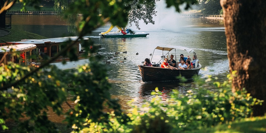 Beautiful view of a river boat bridge surrounded by green trees under blue sky