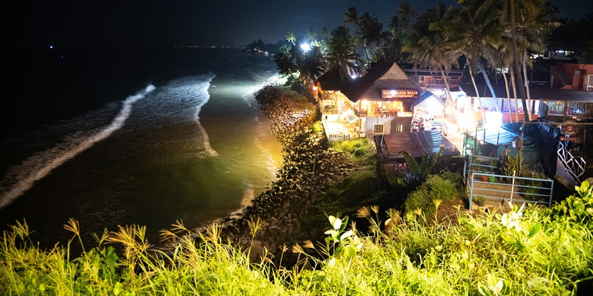 Image of a beach restaurant view from a hill top with vibrant lights, serene environment near the sea