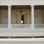 White neoclassical hall with tall columns in an elegant building with a person in view