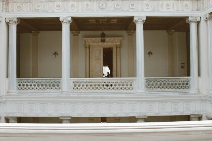 White neoclassical hall with tall columns in an elegant building with a person in view