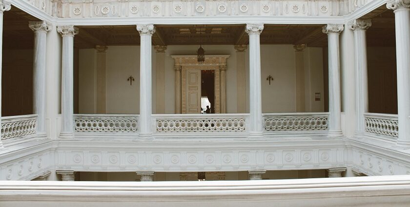 White neoclassical hall with tall columns in an elegant building with a person in view