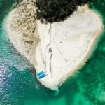 A bird’s eye view of turquoise-blue waters meeting the pristine golden sands in Indonesia.