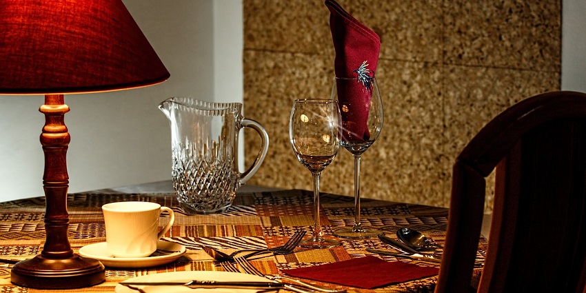 Elegant dinner table set at a restaurant with plates, cutlery, and glasses in soft lighting.