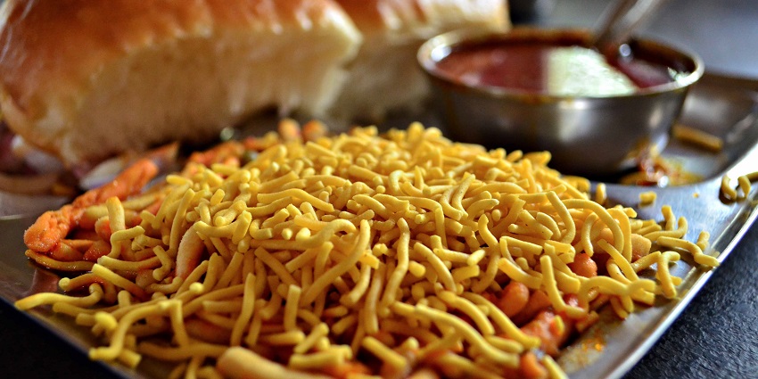 A plate of Maharashtra's Misal Pav, a popular Indian dish, featuring a bowl of spicy curry.