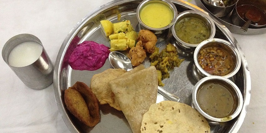 Maharashtrian thali featuring rice, vegetables, chapati, and delicious sweets.