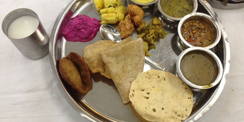 A traditional Maharashtrian thali featuring various dishes, served on a circular platter.