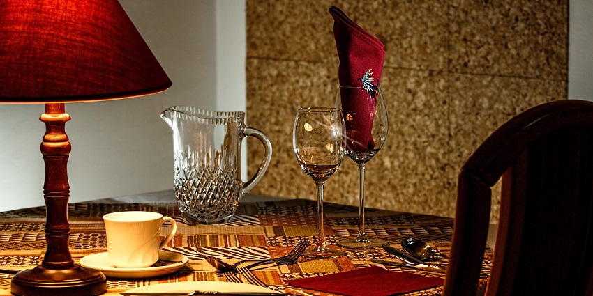 An elegant dinner table is set at a restaurant with plates, cutlery, and glasses in soft lighting.