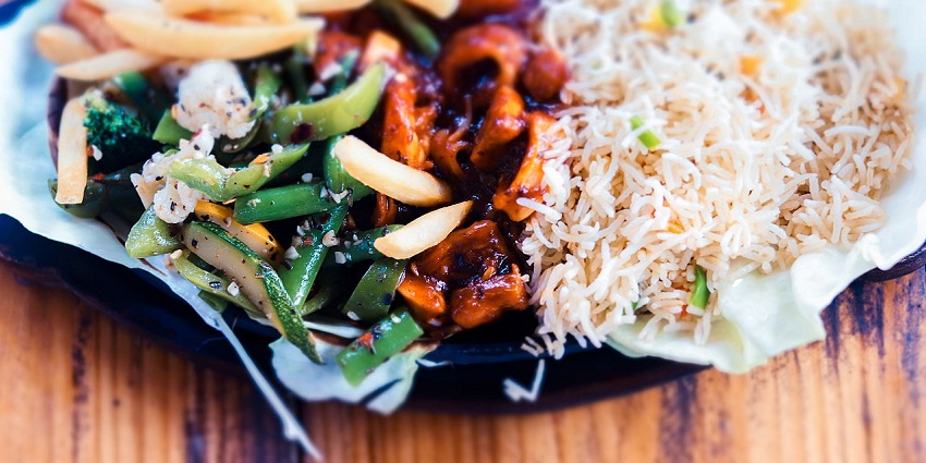 A mouth-watering view of a plate served with cooked dishes during the daytime for all.