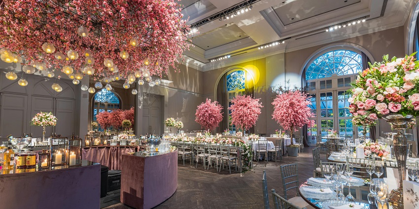 A romantic restaurant hall adorned with cherry trees and candles for an enchanting night.
