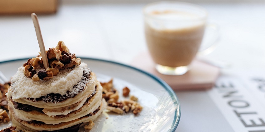 Fluffy pancakes stacked high, drizzled with syrup, served as a delicious breakfast
