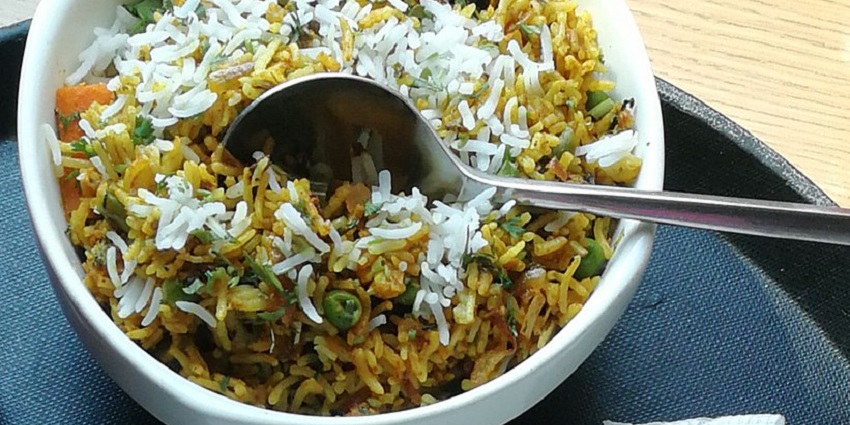Image of Mumbai biryani served on a white container and a tray below in a restaurant